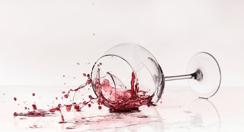 Broken wine glass with red wine spilled